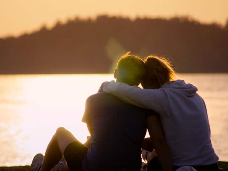 man and woman hugging at sunset