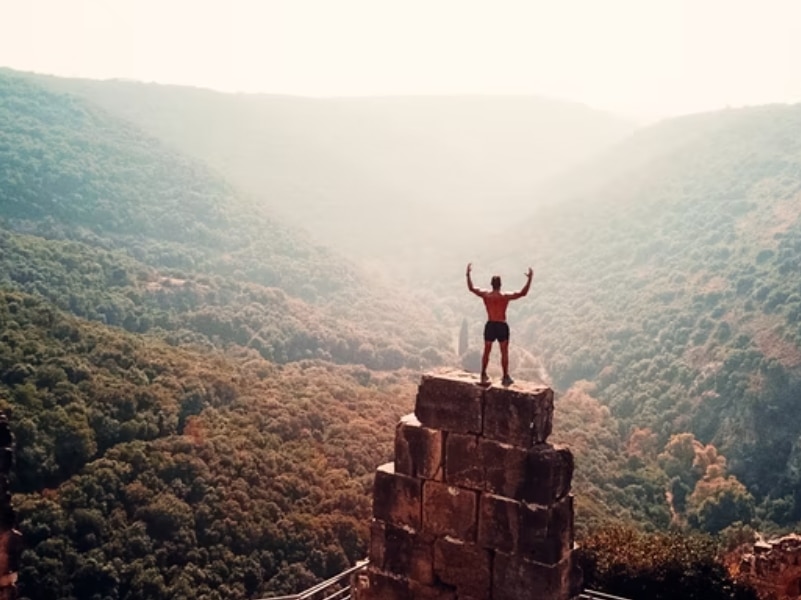 man climbing at top celebrating