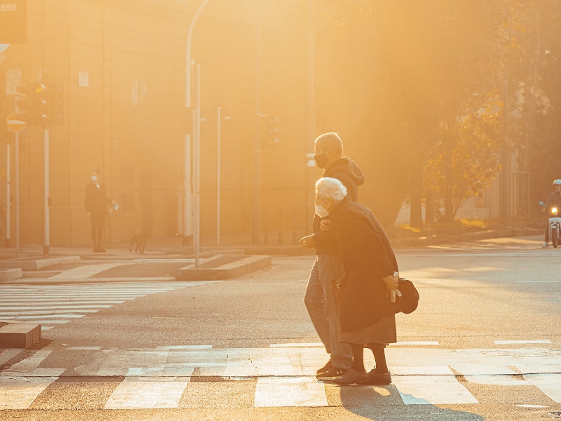 man helping elder cross street