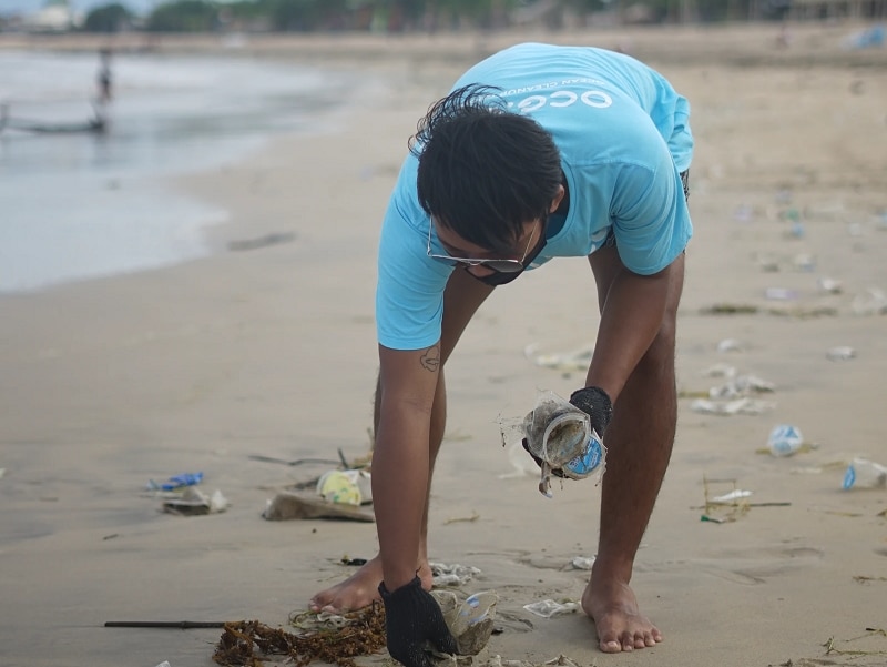 man picking up trash on beach