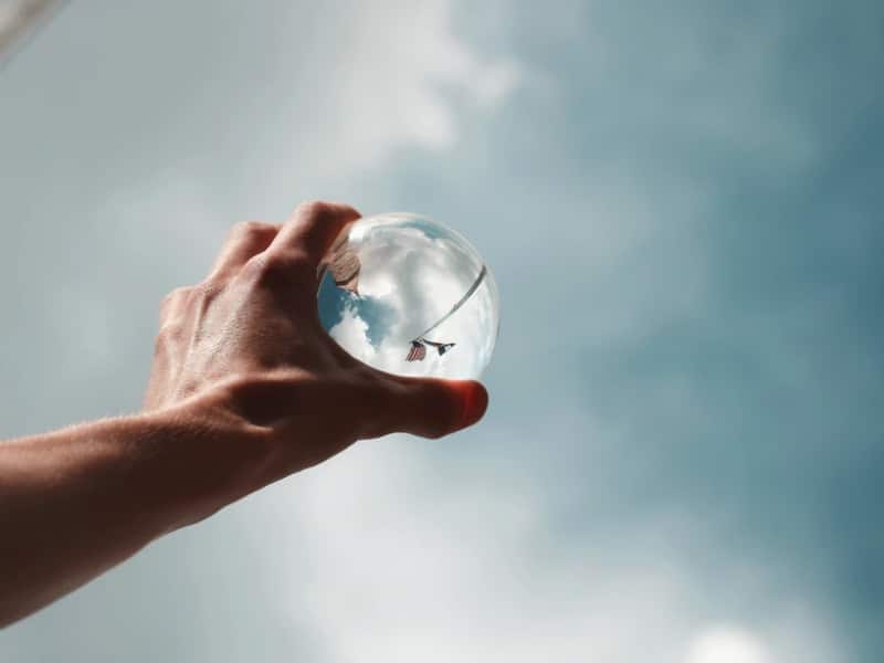 man reaching for glass ball sky