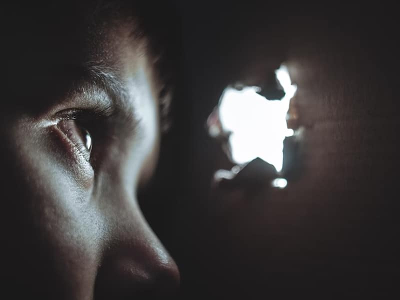 person peeking out of hole in wall