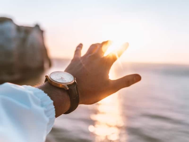 person reaching out with hand towards sun