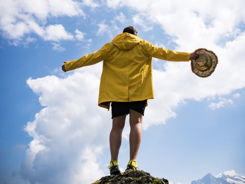 person standing on mountain arms wide