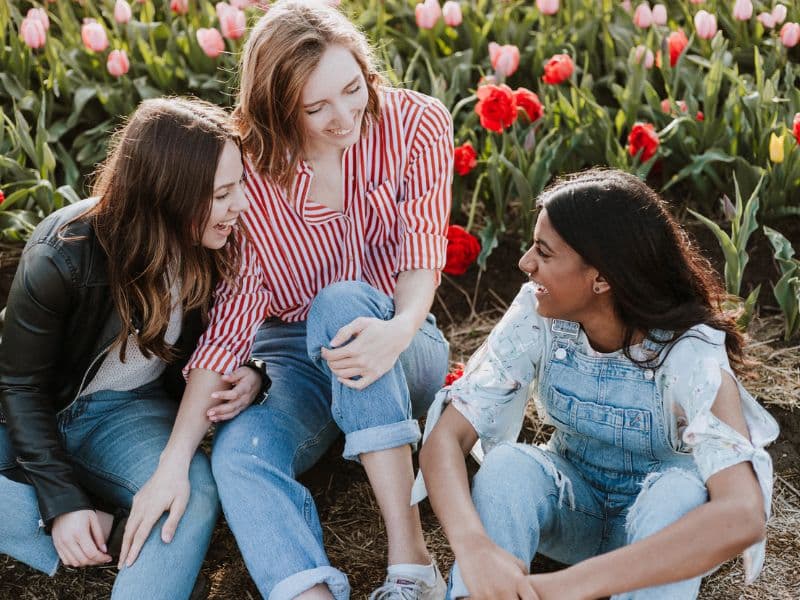 three happy women sitting near flowers