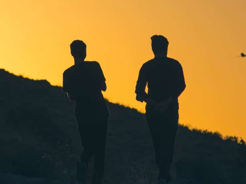 two men walking at sunset