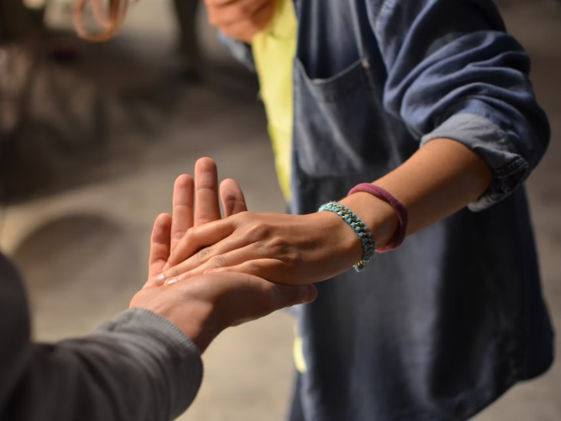 two persons holding helping hands