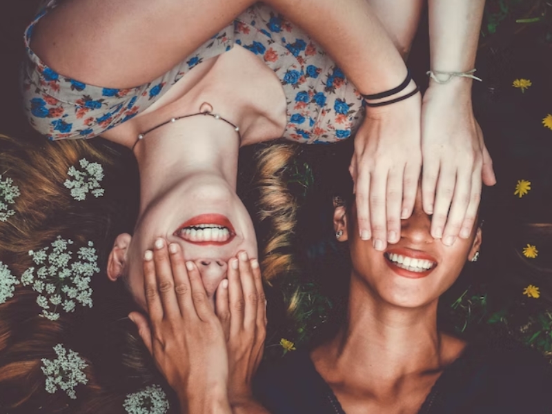 two woman covering their smiles