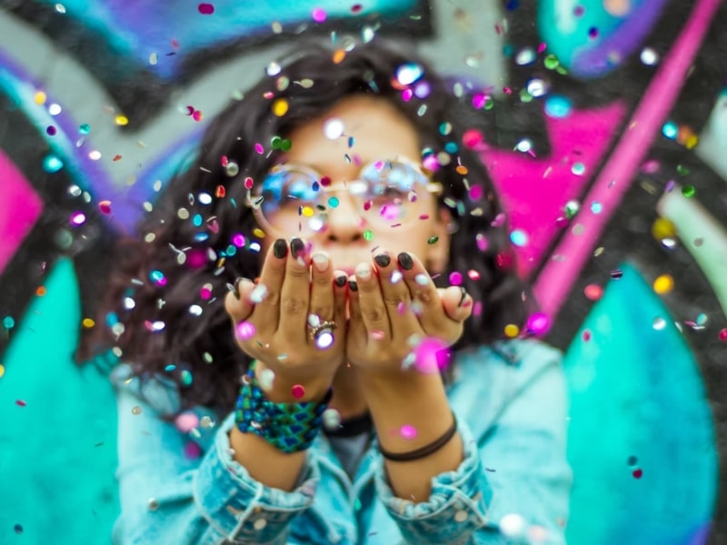 woman blowing confetti colors