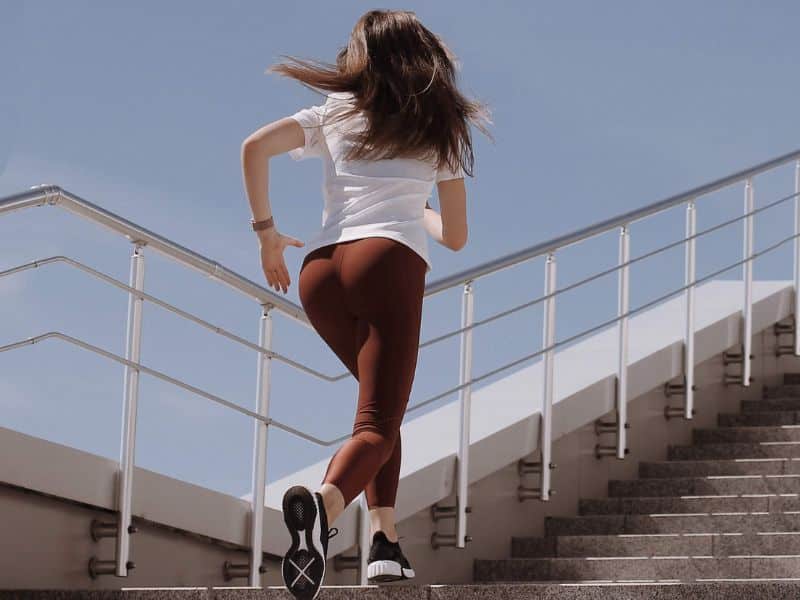 Woman in White Shirt and Leggings Running on the Concrete Stairs