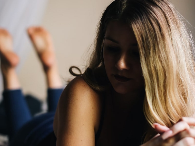 woman on bed contemplating