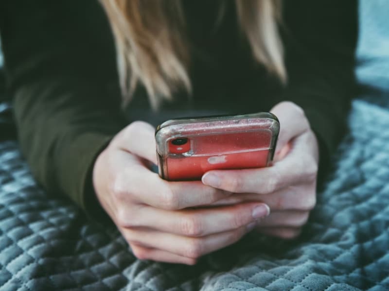 woman on her phone while laying in bed