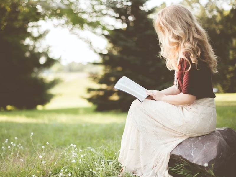 woman reading book outside alone