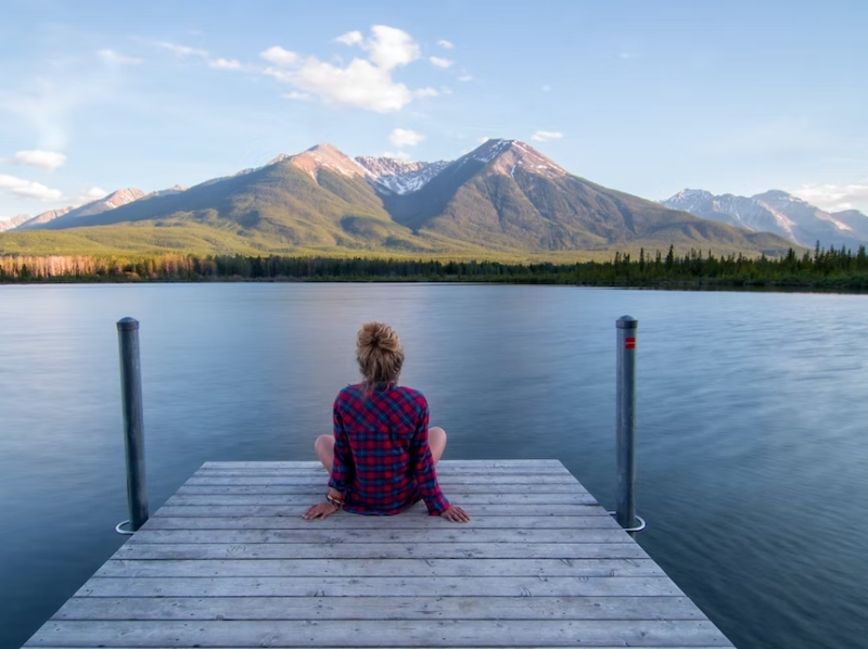 woman sitting on dock at lake