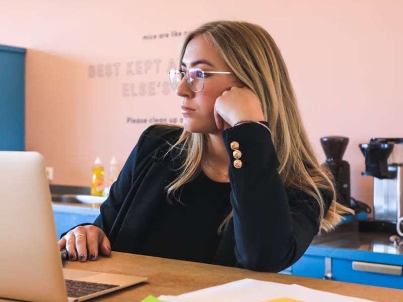 woman thinking behind laptop